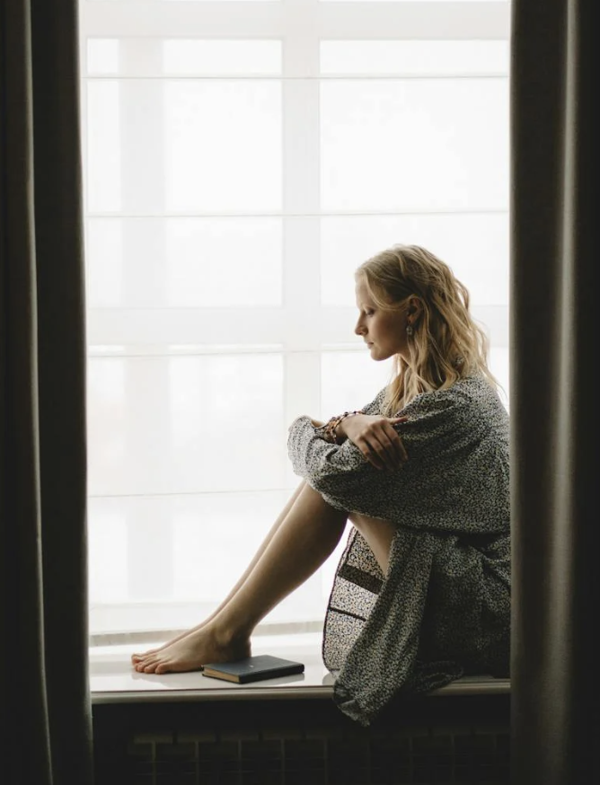 Kvinde sidder ved vindue midt i en livskrise – når alt føles usikkert